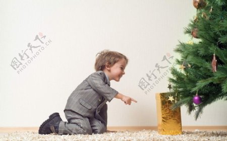 欢笑的儿童指着圣诞树下的礼物图片