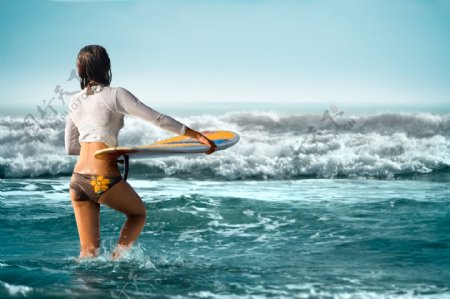 拿着冲浪板向海里走去的女人图片