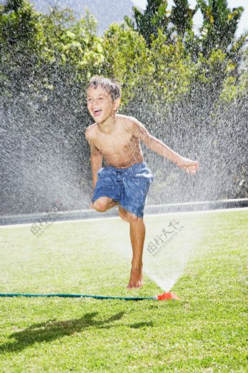 草地上玩水的小男孩图片