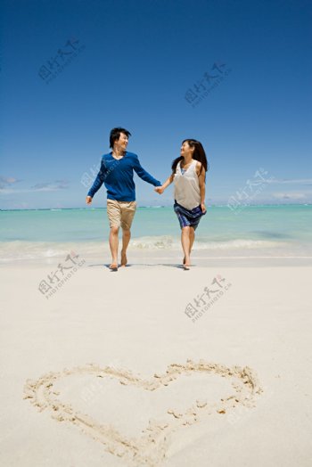 牵手走在沙滩上的快乐情侣图片