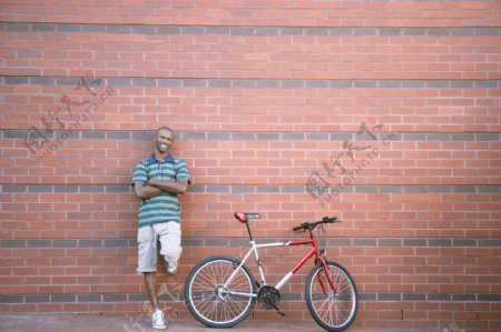 靠在墙壁上的男人与自行车图片