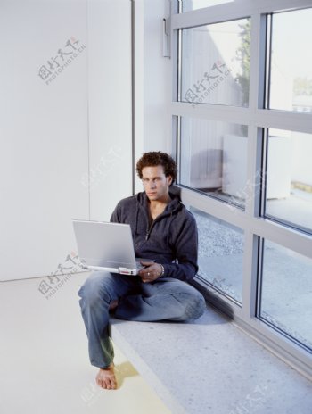 坐在窗台上玩电脑的男人图片