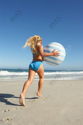 沙滩上玩皮球的美女图片