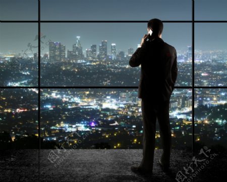 站在玻璃窗前听电话的男人图片