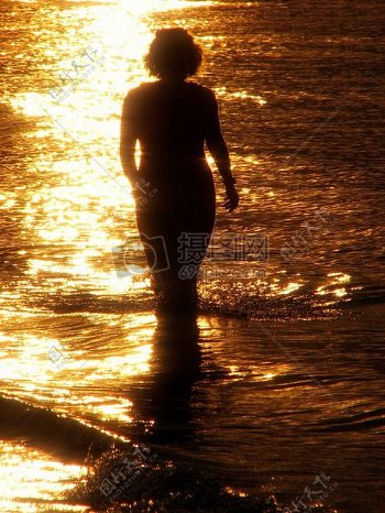 夕阳下漫步在河里的女子