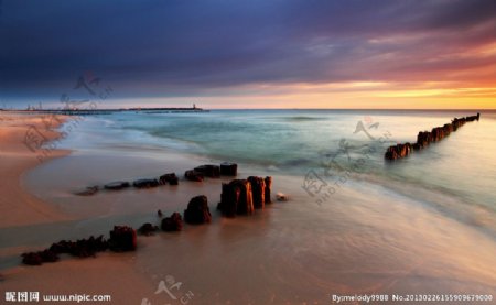 夕阳海浪沙滩木桩图片