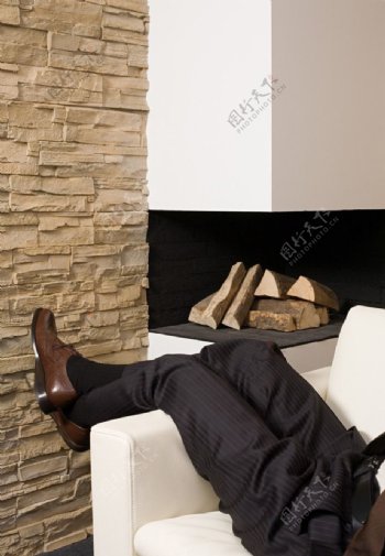 躺在沙发上休息的商务人物腿部特写破碎的墙图片