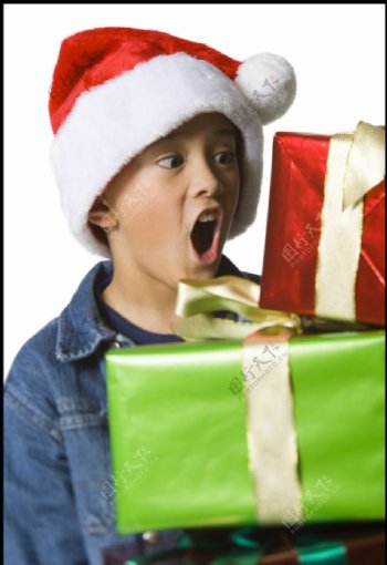 带圣诞帽冲着礼盒呼喊的小男孩图片