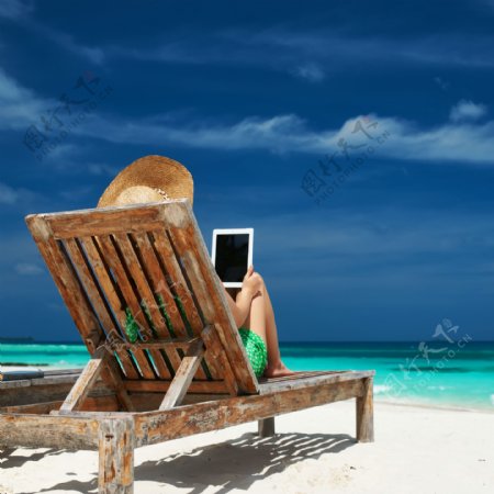 海边躺椅上看平板的女人图片