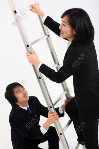 男士为爬梯子的女性扶着图片