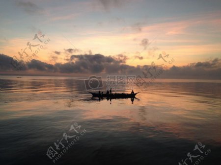 剪影渔民在船在海上标签在蓝水和多云的天空日落