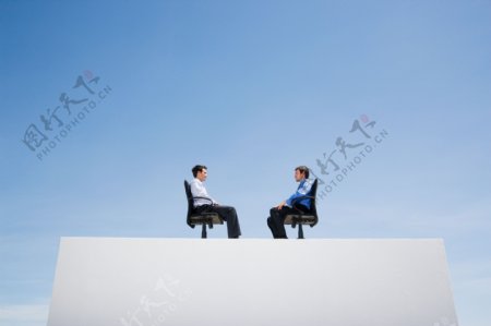面对面坐在沙发上的两个男人图片