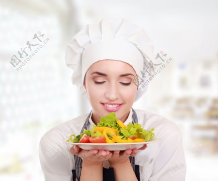 手捧蔬菜沙拉的漂亮女厨师图片