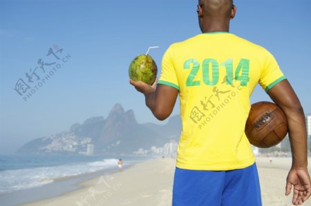 海边拿椰果与足球的球员图片