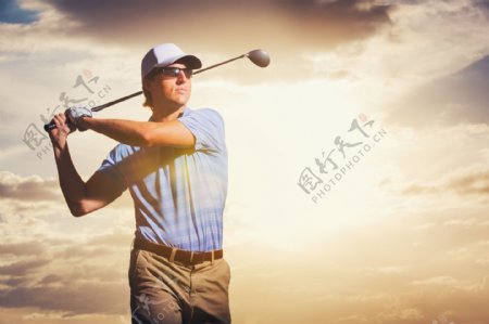 天空下挥动高尔夫球杆的男人图片