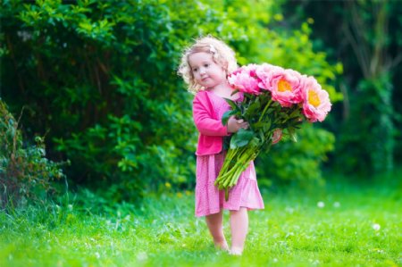 草地上捧着花朵的小女孩图片