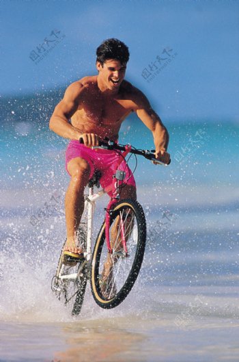 海滩上骑自行车的外国男士图片