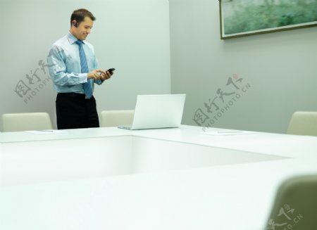 会议室里看手机的男人图片