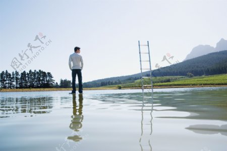 站立在水面上的男人与梯子图片