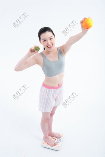 拿着水果量体重的快乐女孩图片图片