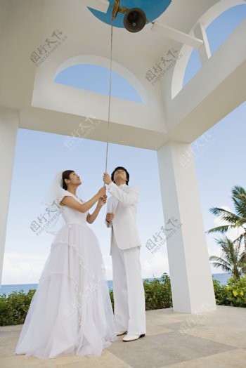 握着钟绳穿着婚纱和礼服的男女图片图片