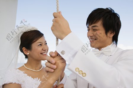 面带笑容穿着婚纱礼服手握绳子的男女图片图片