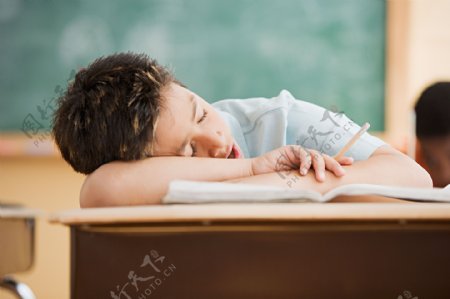 趴在课桌上睡觉的小男孩图片